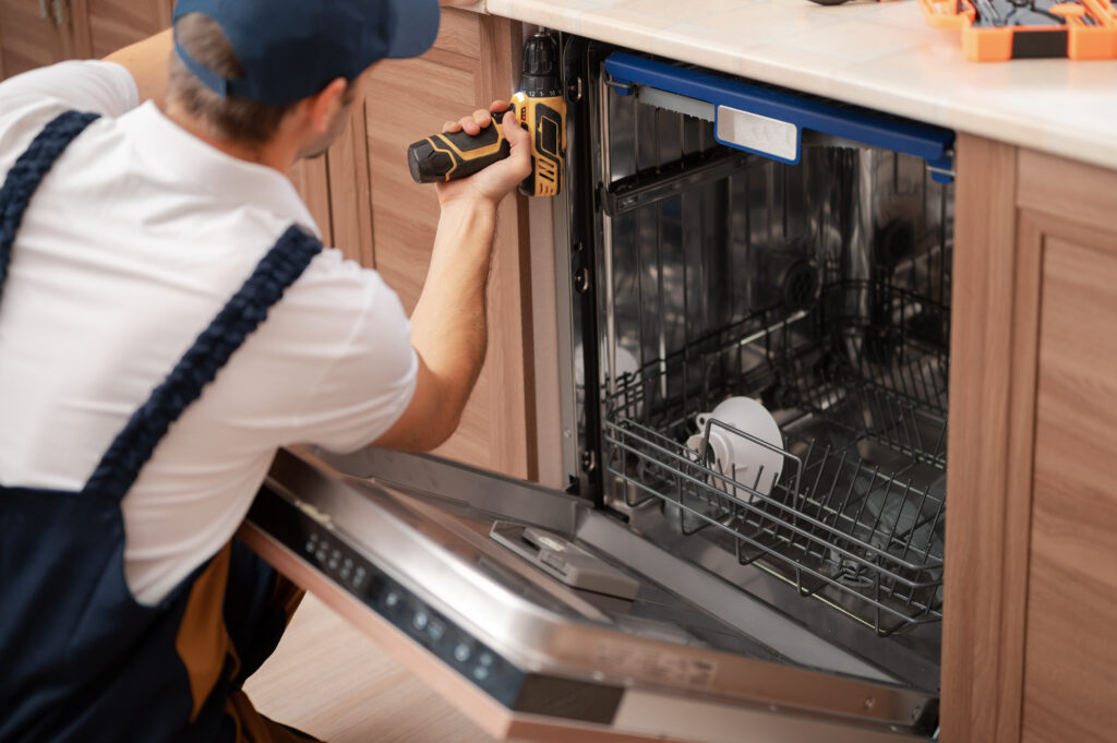 Technician repairing a dishwasher in a kitchen